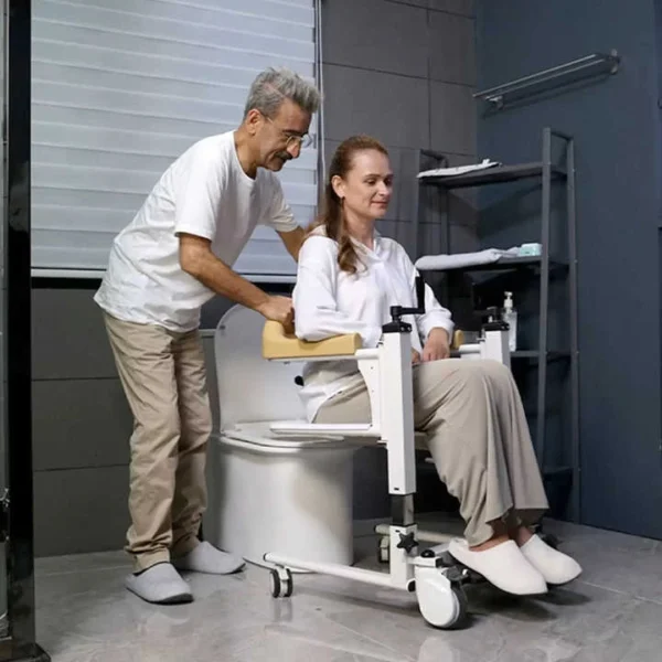 Caregiver transferring patient from shift chair onto home toilet